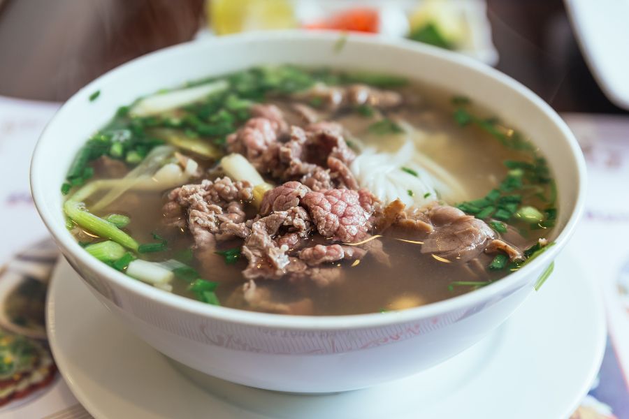 Bol de pho bo garni d’herbes fraîches et de tranches de bœuf, un specialité de Hanoï.