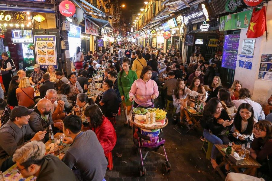 Rue Ta Hien à Hanoï la nuit, animée par des bars et des tabourets en plastique remplis de visiteurs et de locaux.