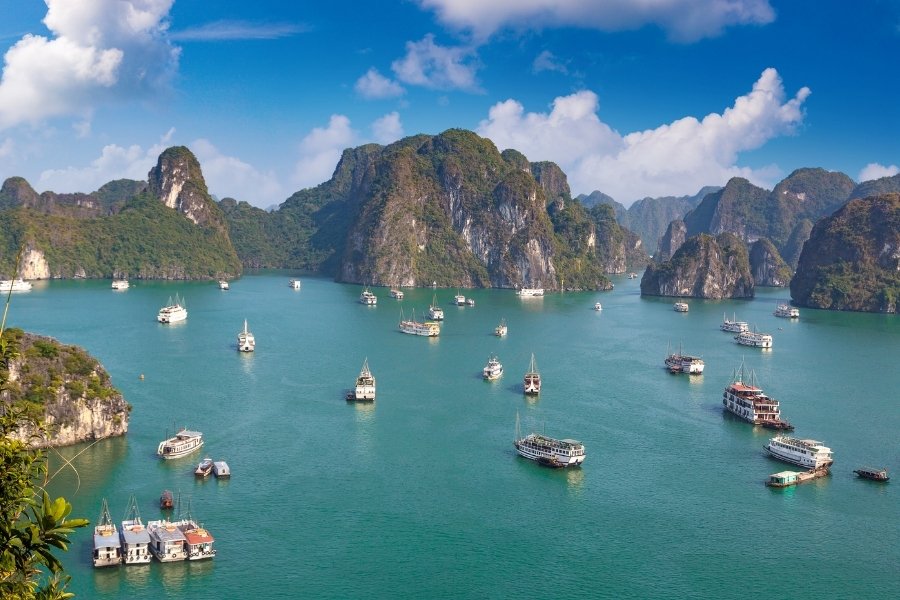 Baie d’Ha Long au Vietnam avec des karsts calcaires émergent des eaux émeraude sous un ciel bleu.
