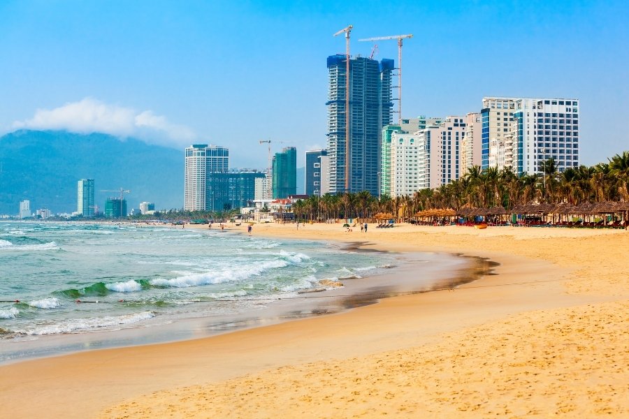 Plage de My Khe à Da Nang avec du sable doré, des eaux claires et des palmiers sous un ciel ensoleillé.