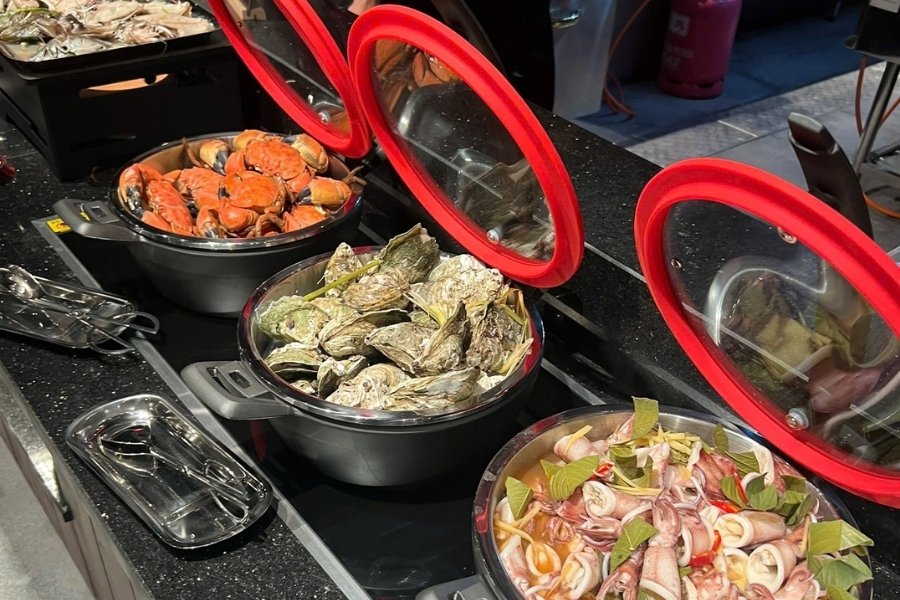 Fruits de mer frais avec huîtres grillées, crabes bouillis et calmars cuits à la vapeur dans une marmite au restaurant Hong Hanh, l'un des meilleurs restaurants de Halong.