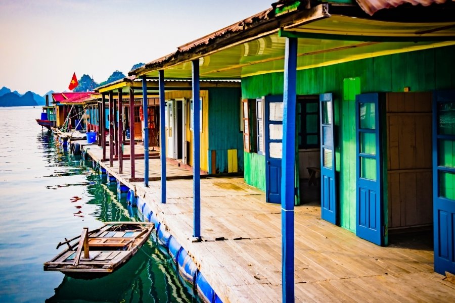 Maisons flottantes colorées du village Cua Van à Halong, nichées parmi les îlots karstiques.