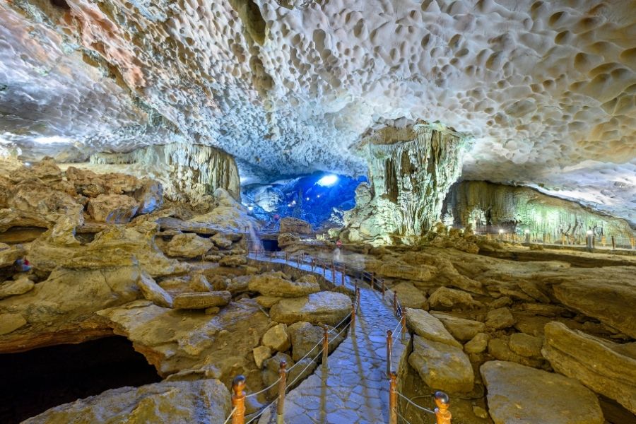 Intérieur de la grotte Sung Sot a Halong, avec stalactites illuminées et formes rocheuses fantastiques.