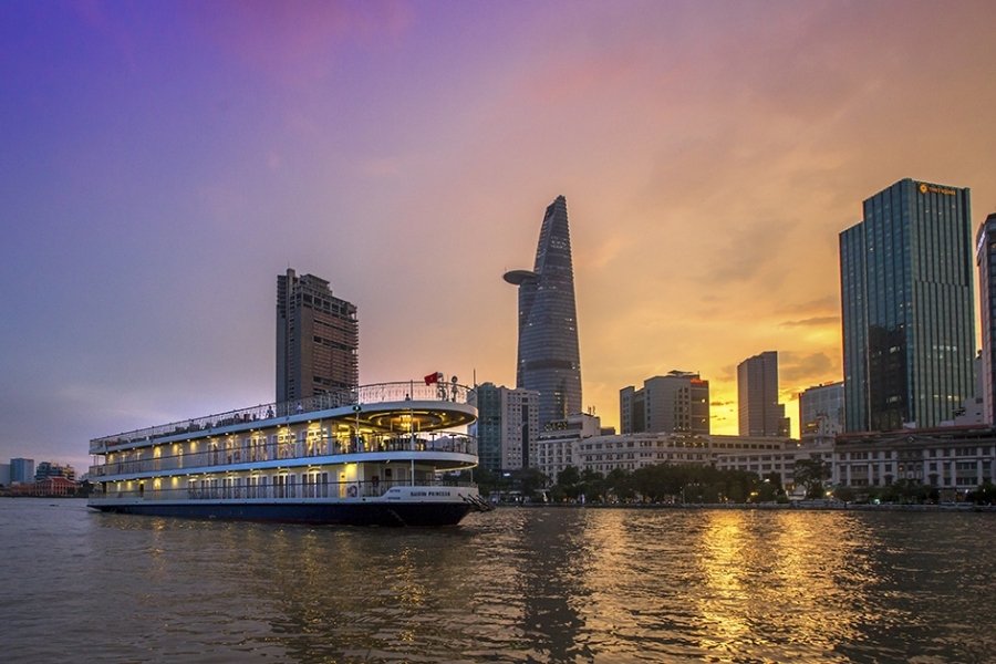 Bateau naviguant sur le fleuve Sài Gòn à Ho Chi Minh Ville, avec la skyline illuminée en arrière-plan.