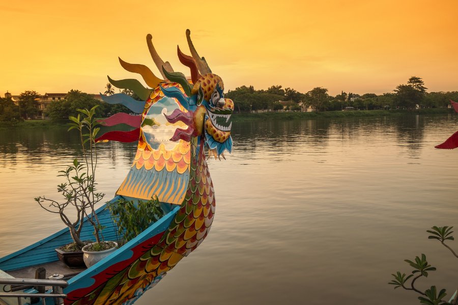 Bateau-dragon sur la rivière des Parfums à Hue, avec rives verdoyantes en toile de fond.