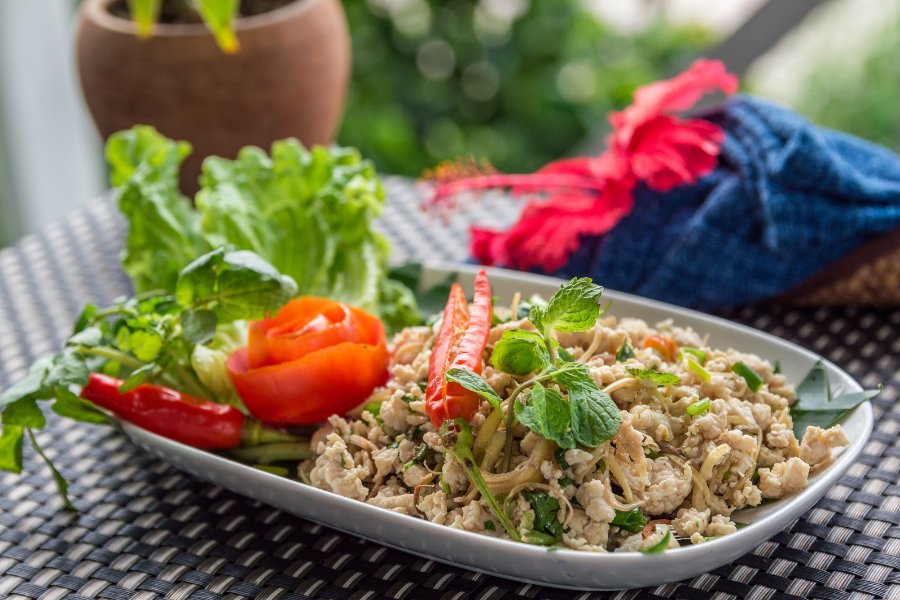 Plat de laap lao avec du porc haché, herbes fraîches et riz gluant, servi dans un restaurant traditionnel.