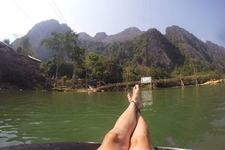 Touriste faisant du tubing sur la rivière Nam Song à Vang Vieng, entourés de pics karstiques et de rizières.