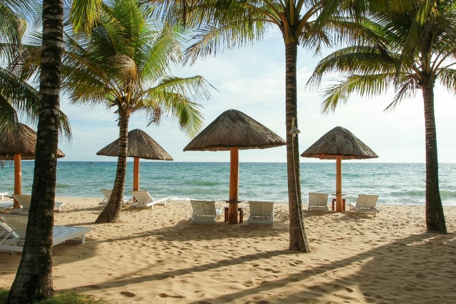 Plage de Bai Sao a Phu Quoc avec sable blanc, eaux claires et cocotiers sous un ciel bleu.