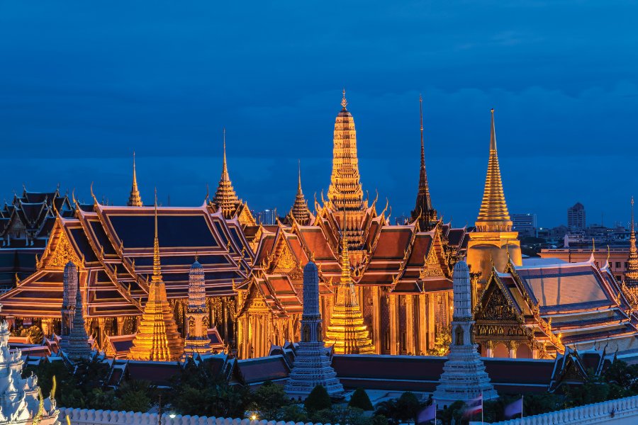 Le Grand Palais de Bangkok illuminé la nuit, avec ses dorures et mosaïques, un site incontournable de la culture thaïlandaise.