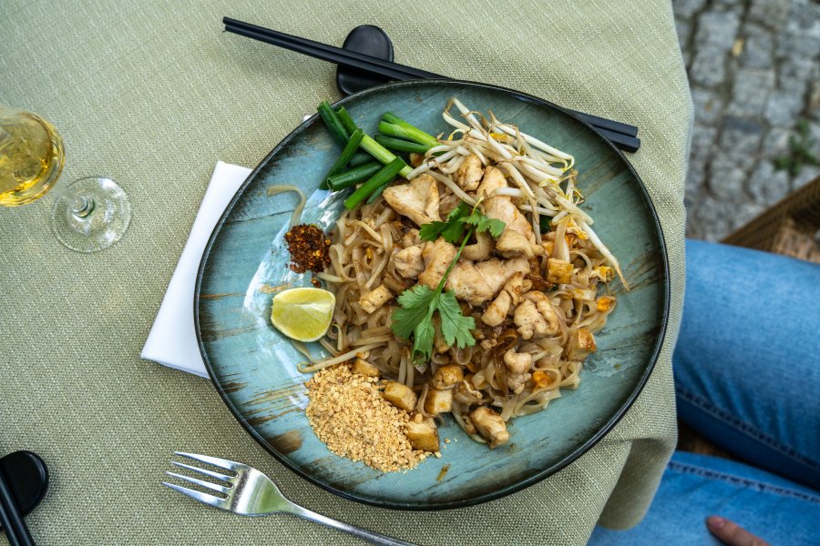 Plat de Pad Thai garni de crevettes et de cacahuètes, servi dans un restaurant thaïlandais.