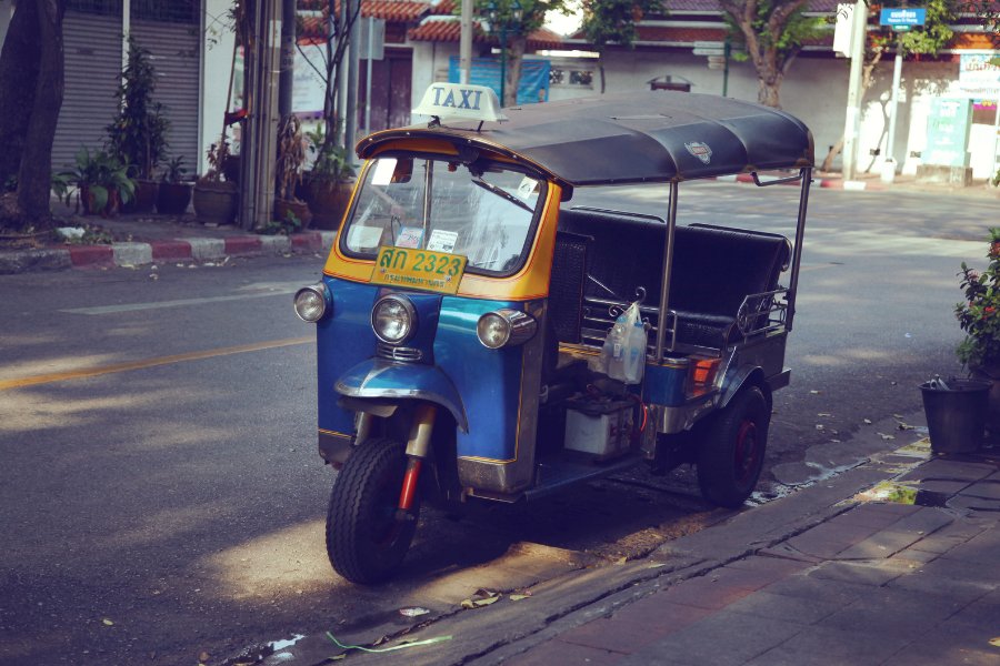 Tuk-tuk bleu et jaune dans les rues animées de Bangkok, un mode de transport emblématique de la Thaïlande.